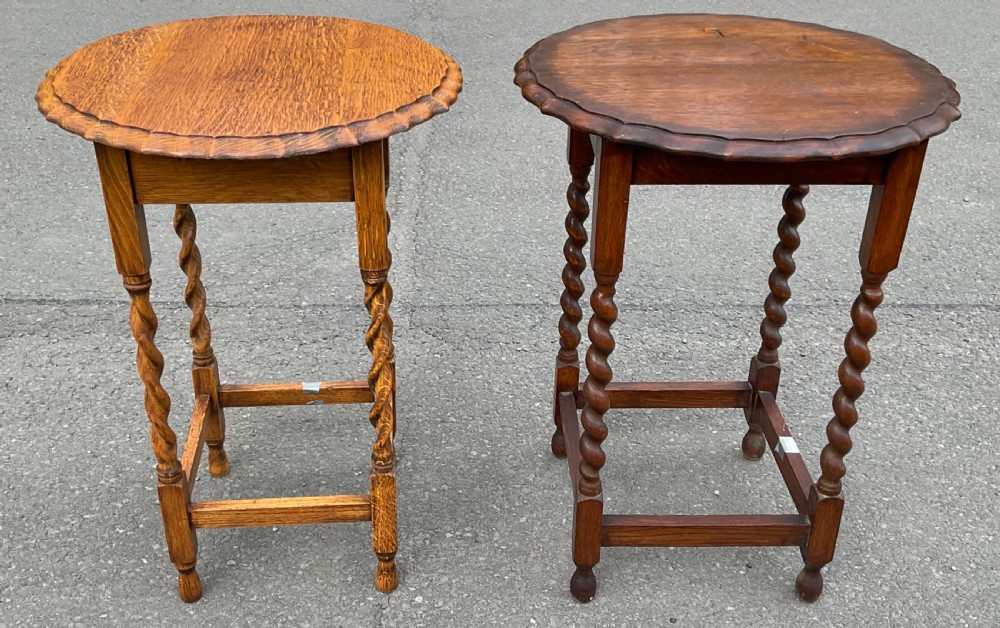 A pair of round oak side tables featuring piecrust scalloped edges, barley twist legs, and square perimeter stretchers.