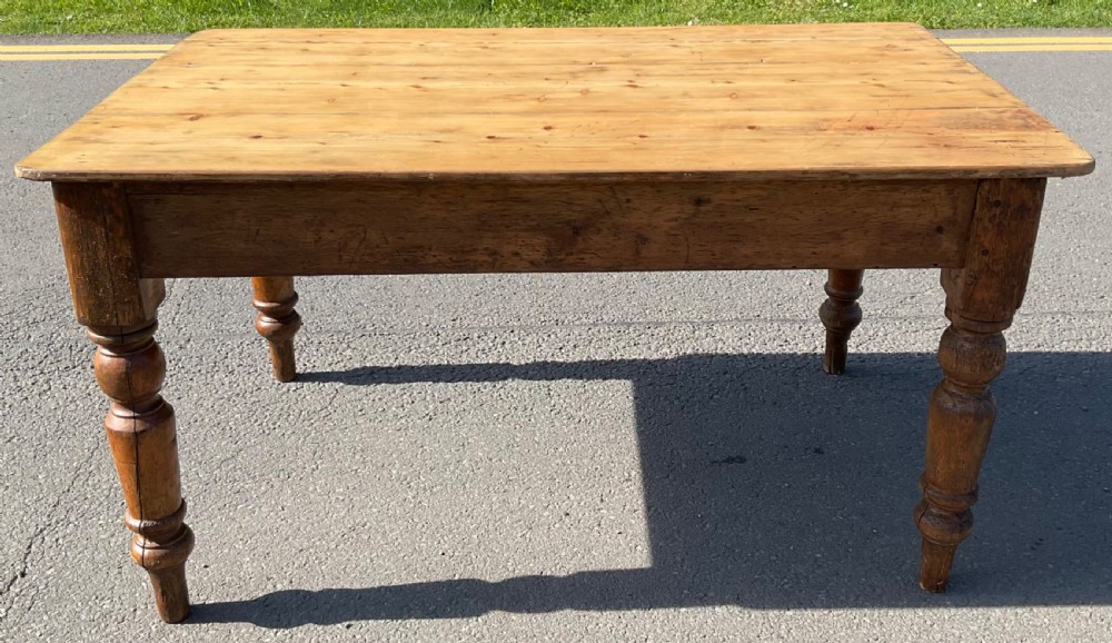 A rectangular Victorian pine kitchen table featuring a planked wood top and four turned wooden legs. View II