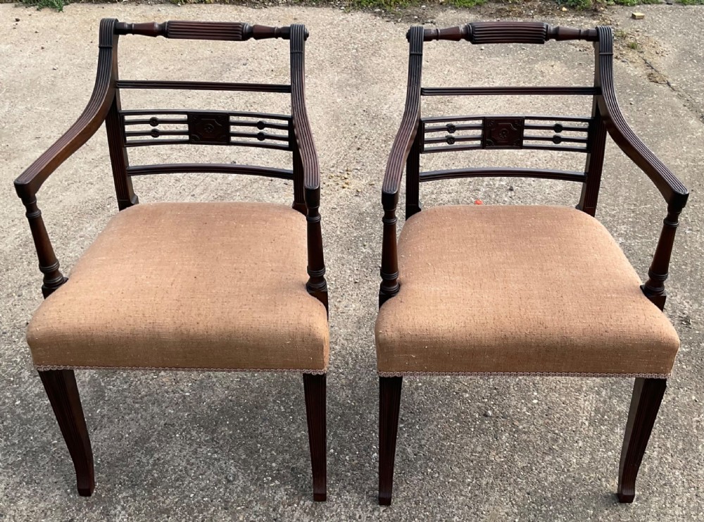 A pair of antique Georgian mahogany carver armchairs with reeded front legs, carved horizontal back splats, and neutral fabric seats. View IV