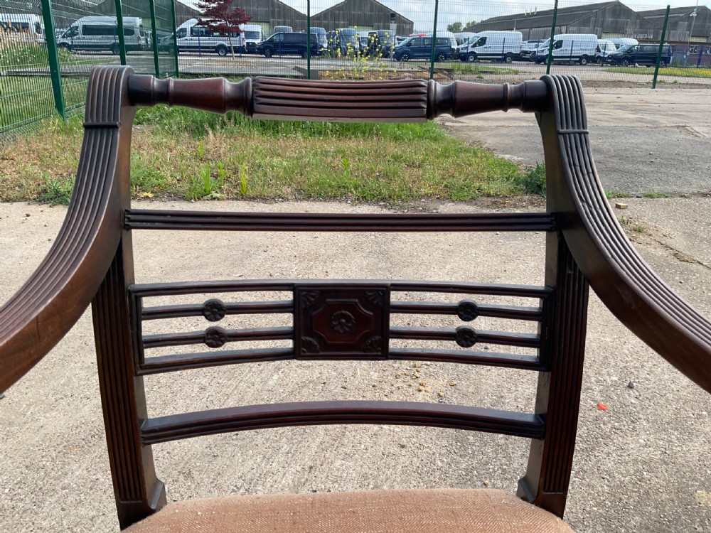 A pair of antique Georgian mahogany carver armchairs with reeded front legs, carved horizontal back splats, and neutral fabric seats. View VI
