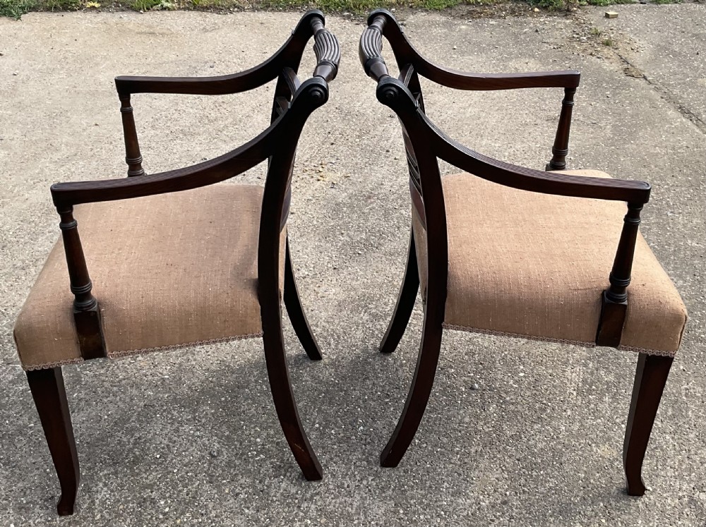 A pair of antique Georgian mahogany carver armchairs with reeded front legs, carved horizontal back splats, and neutral fabric seats. View VIII