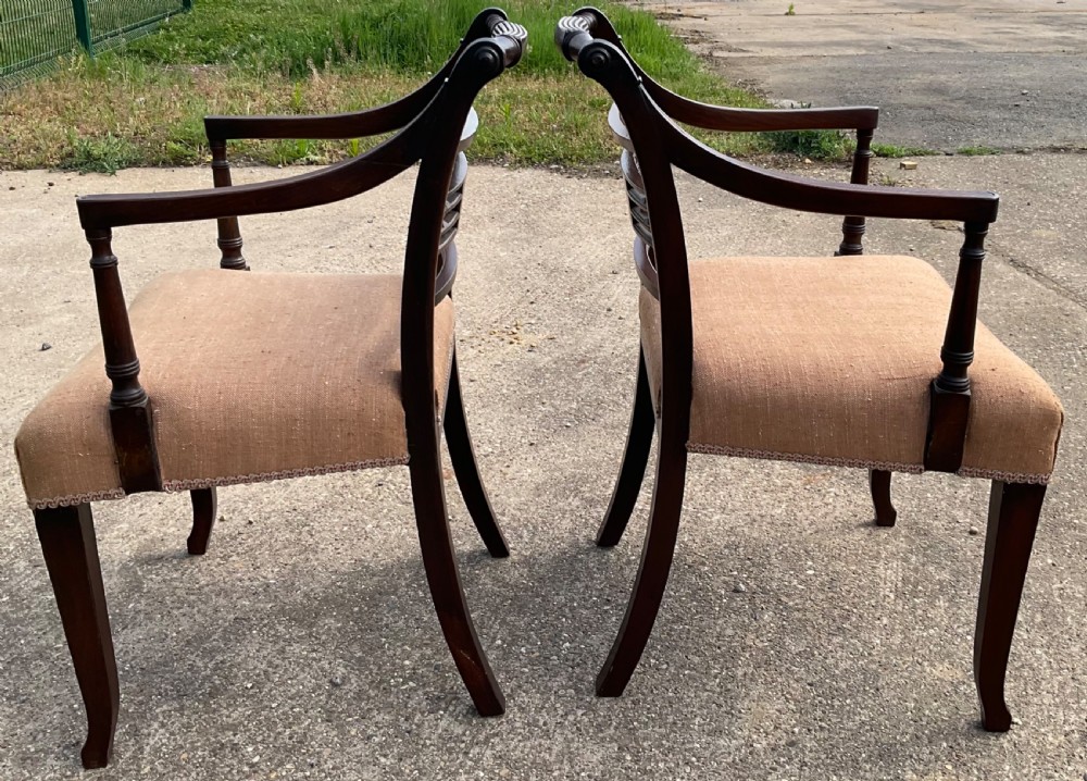 A pair of antique Georgian mahogany carver armchairs with reeded front legs, carved horizontal back splats, and neutral fabric seats. View IX