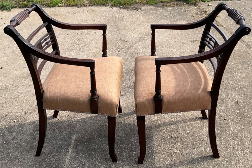 A pair of antique Georgian mahogany carver armchairs with reeded front legs, carved horizontal back splats, and neutral fabric seats. View XI