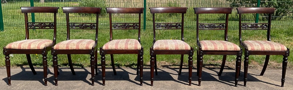 A set of six dark rosewood Regency dining chairs featuring carved bar back rails, turned front legs, and striped upholstered seats. View II