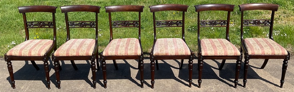 A set of six dark rosewood Regency dining chairs featuring carved bar back rails, turned front legs, and striped upholstered seats. View V
