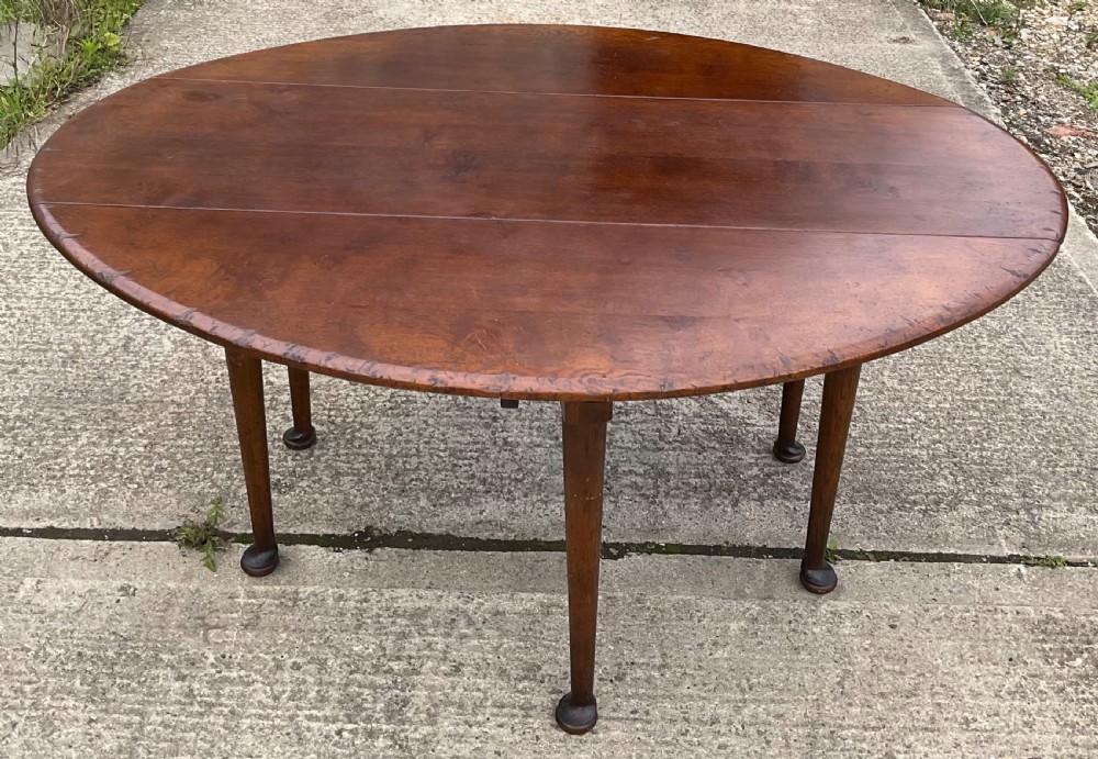 A large oval mahogany dropleaf dining table with tapered legs terminating in pad feet.