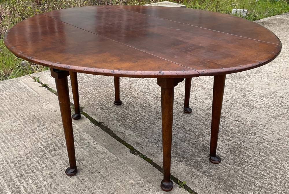 A large oval mahogany dropleaf dining table with tapered legs terminating in pad feet. View II