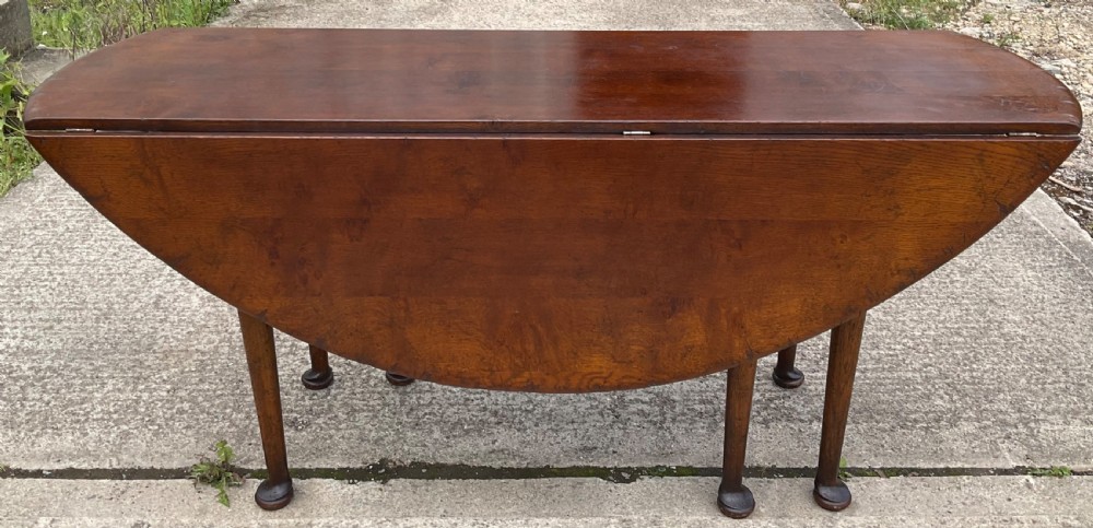 A large oval mahogany dropleaf dining table with tapered legs terminating in pad feet. View V