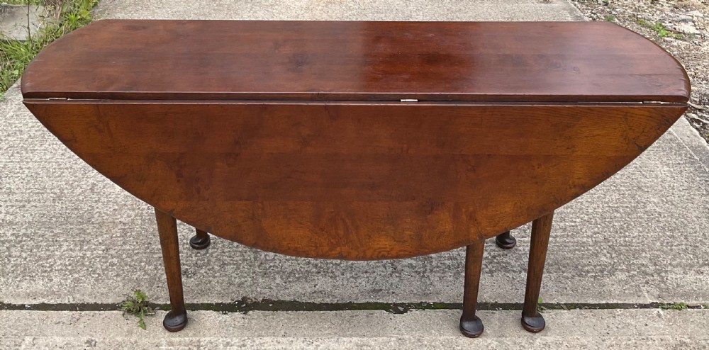 A large oval mahogany dropleaf dining table with tapered legs terminating in pad feet. View VI