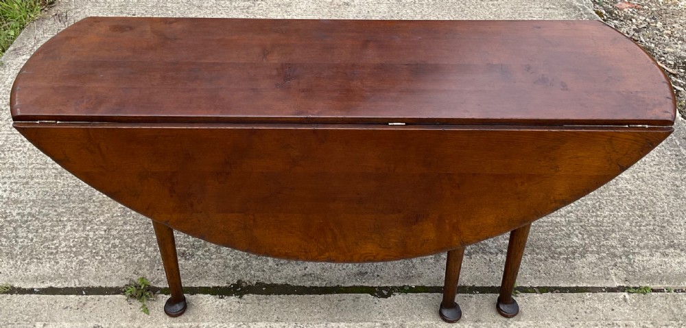 A large oval mahogany dropleaf dining table with tapered legs terminating in pad feet. View VII