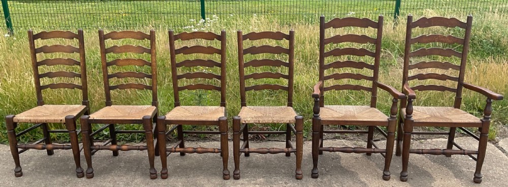 A set of six warm brown wood ladderback dining chairs with hand-woven rush seats, comprising four side chairs and two carver armchairs. View II