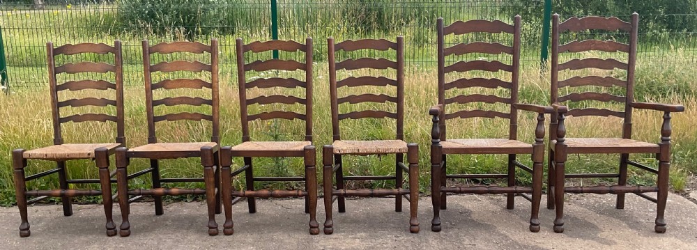 A set of six warm brown wood ladderback dining chairs with hand-woven rush seats, comprising four side chairs and two carver armchairs. View III