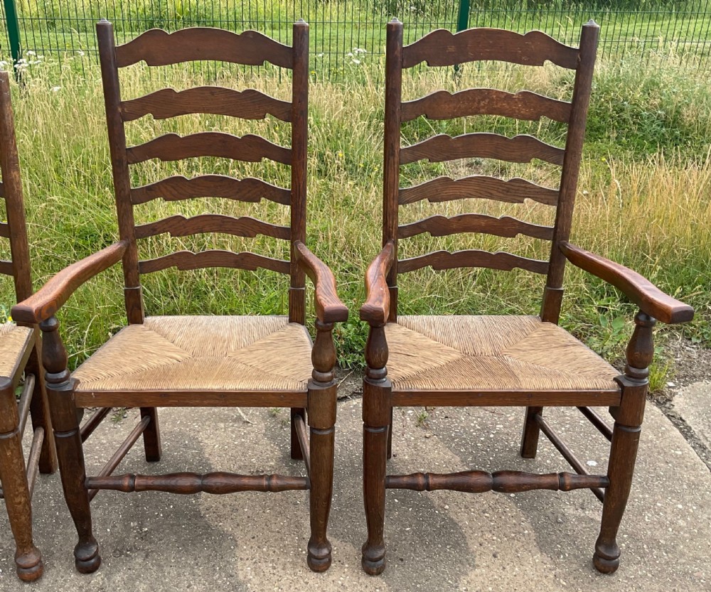 A set of six warm brown wood ladderback dining chairs with hand-woven rush seats, comprising four side chairs and two carver armchairs. View IV