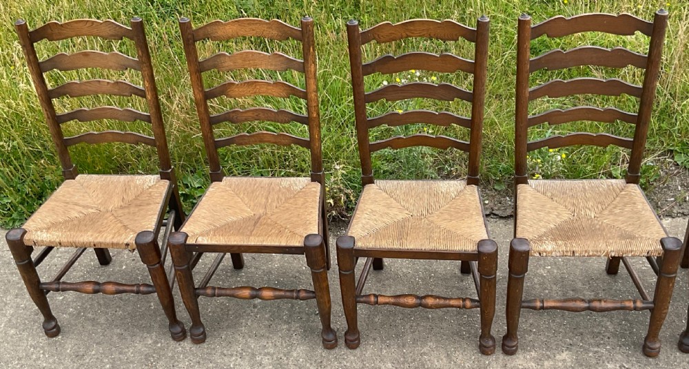 A set of six warm brown wood ladderback dining chairs with hand-woven rush seats, comprising four side chairs and two carver armchairs. View VI