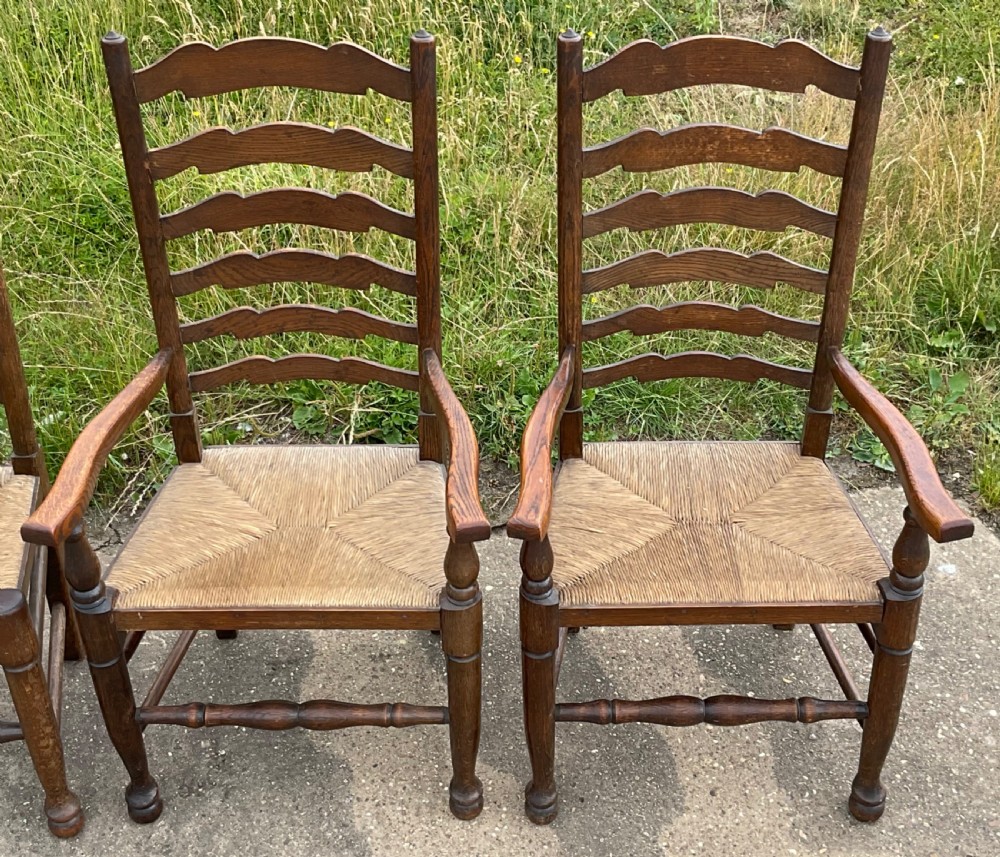 A set of six warm brown wood ladderback dining chairs with hand-woven rush seats, comprising four side chairs and two carver armchairs. View VII