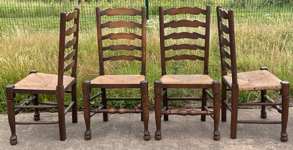 A set of six warm brown wood ladderback dining chairs with hand-woven rush seats, comprising four side chairs and two carver armchairs. View IX