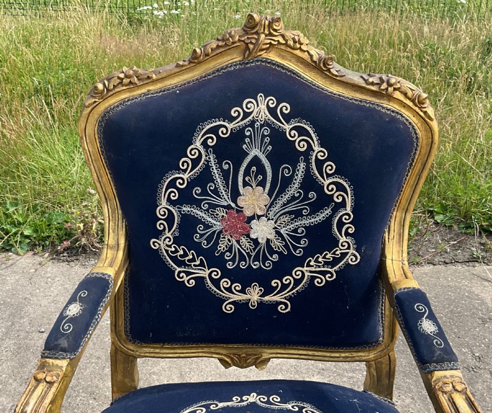 A Victorian giltwood armchair featuring a gold carved frame, cabriole legs, padded armrests, and dark blue velvet upholstery decorated with central floral embroidery. View III