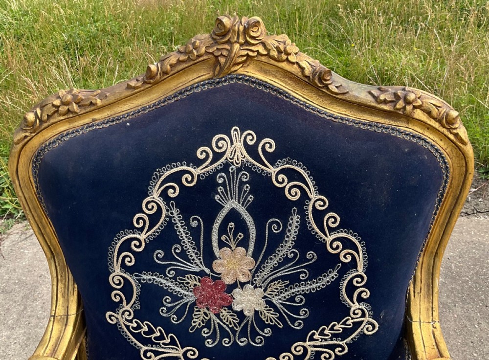 A Victorian giltwood armchair featuring a gold carved frame, cabriole legs, padded armrests, and dark blue velvet upholstery decorated with central floral embroidery. View VII