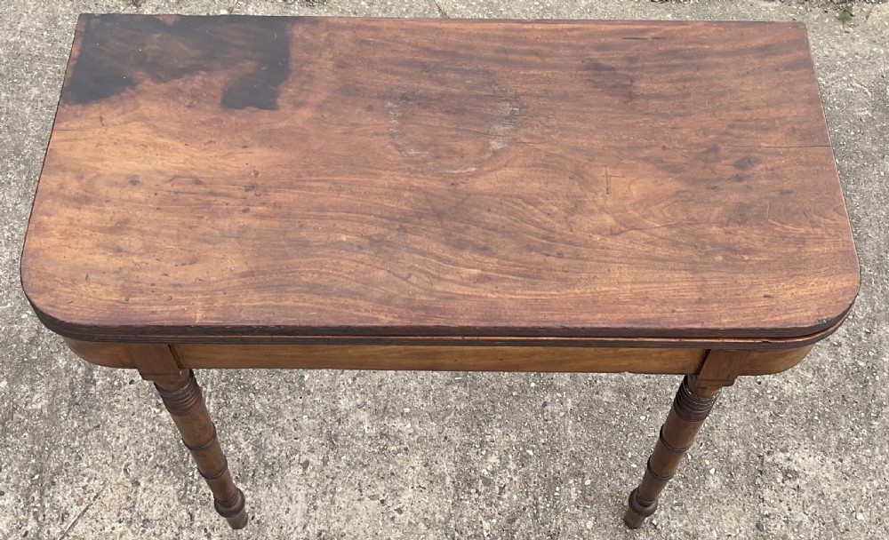 A Georgian mahogany foldover tea table with ring-turned legs and a reeded edge on a flat concrete surface. View VII