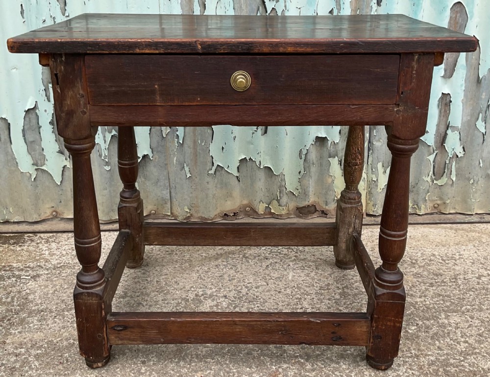 A dark brown antique oak side table featuring a single drawer with a brass knob, turned legs, and a four-piece stretcher base. View III
