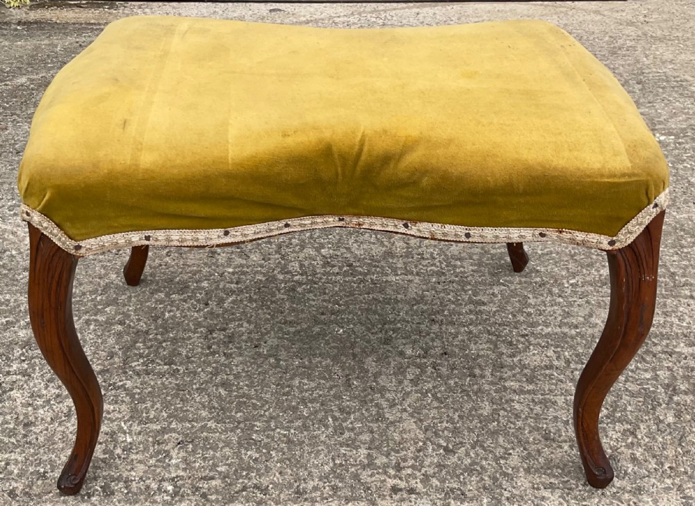 A Victorian low stool featuring a concave olive velvet upholstered seat, trim detail, and four dark carved walnut cabriole legs. View II