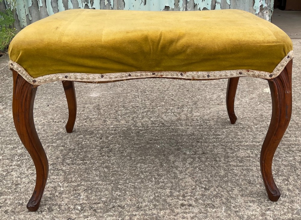 A Victorian low stool featuring a concave olive velvet upholstered seat, trim detail, and four dark carved walnut cabriole legs. View III