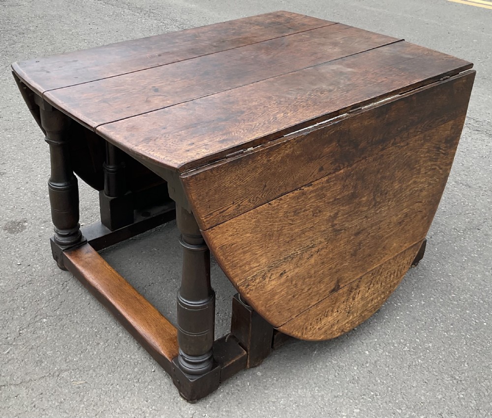 A large antique oak gateleg dining table featuring an oval top with drop leaves, supported by turned legs and stretcher rails. View VI