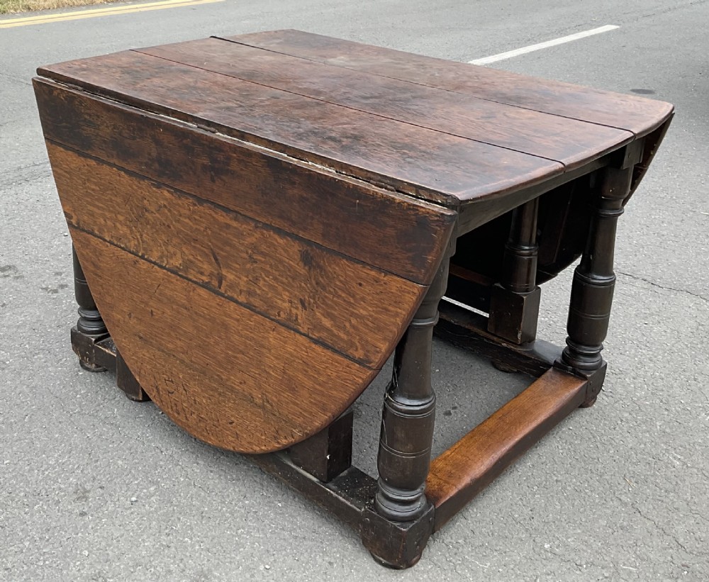A large antique oak gateleg dining table featuring an oval top with drop leaves, supported by turned legs and stretcher rails. View VII
