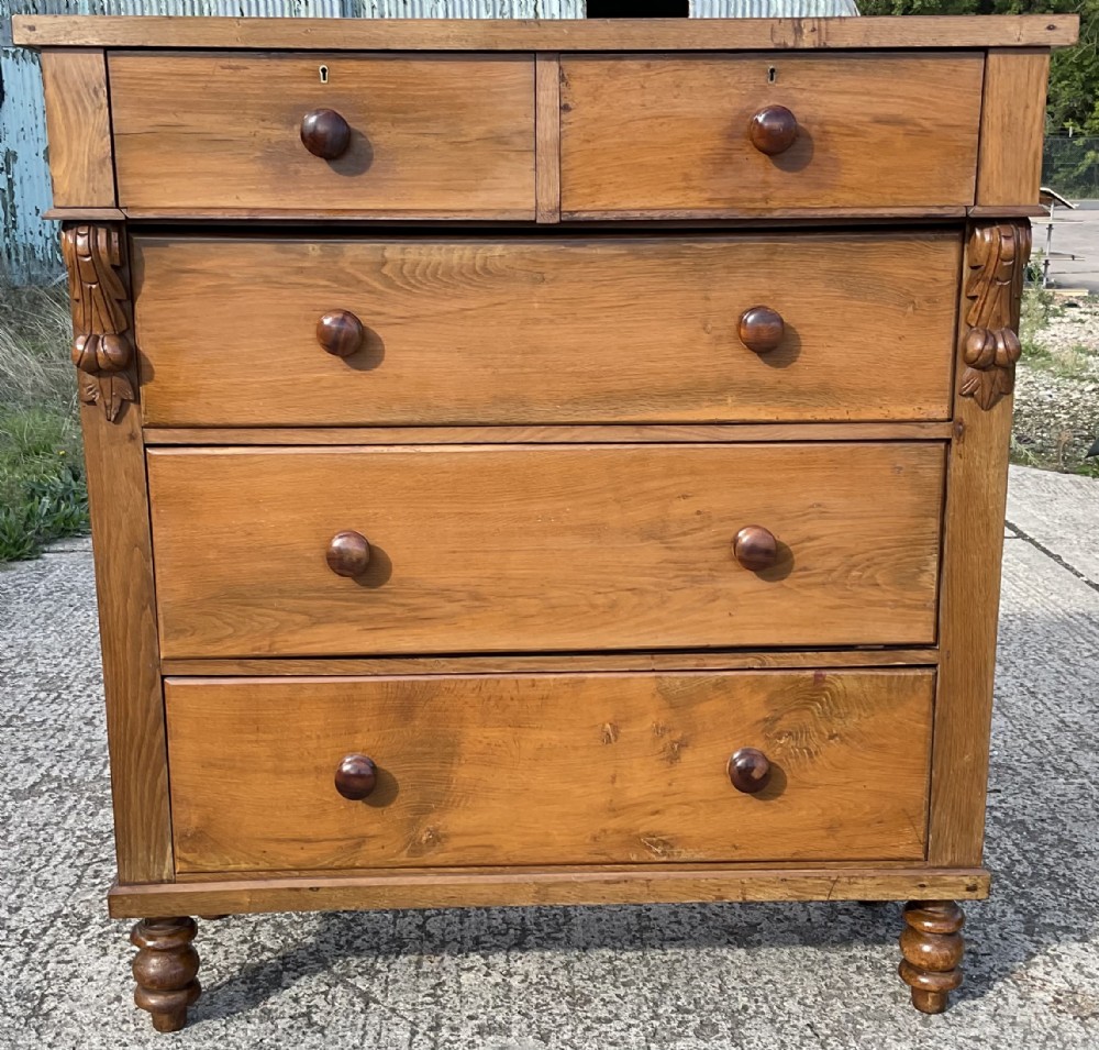 A Victorian satin birch chest of drawers featuring two short upper drawers above three full-width graduated drawers with turned wooden knobs and carved side corbels.