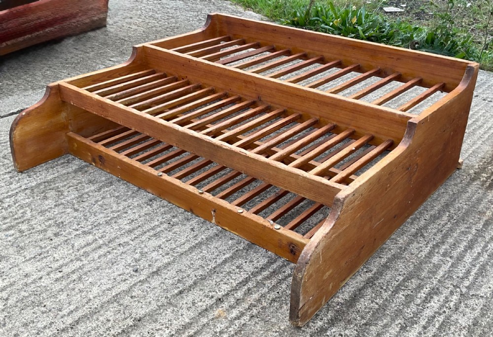 A two-tiered pine hanging kitchen plate rack featuring slatted timber shelves and curved side supports.
