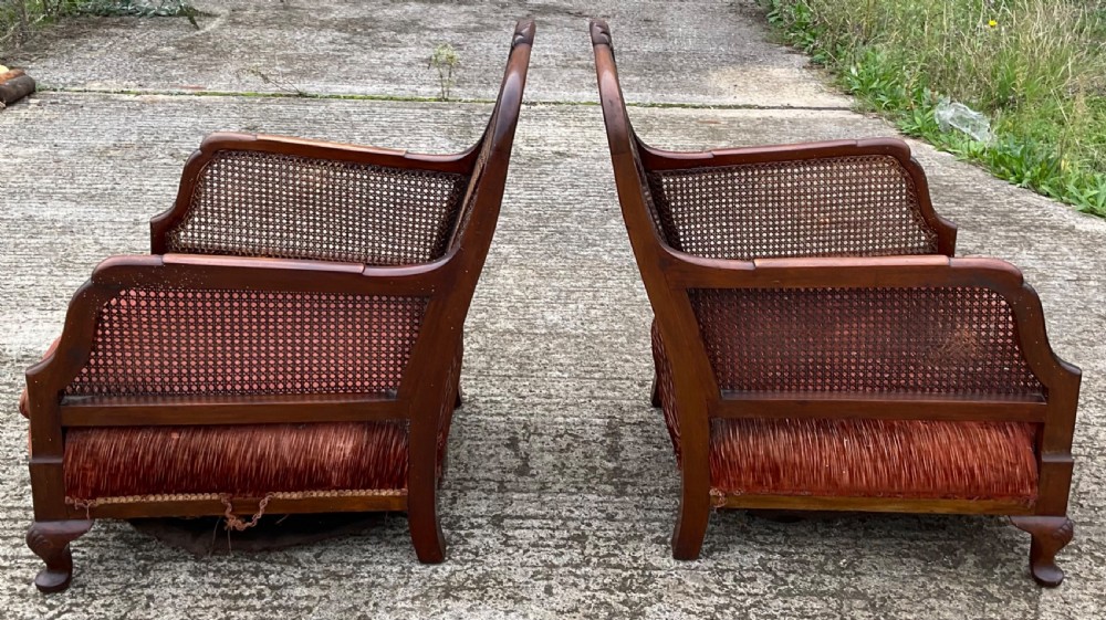 A three-piece antique mahogany lounge suite consisting of a two-seater settee and two matching armchairs with cane side panels, carved central splats, and worn red velvet cushions. View V