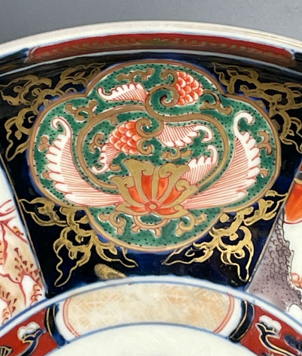 A large circular Japanese Imari porcelain shallow bowl featuring detailed panelled motifs in cobalt blue, iron-red, green, and gold hand-painted enamel. View III