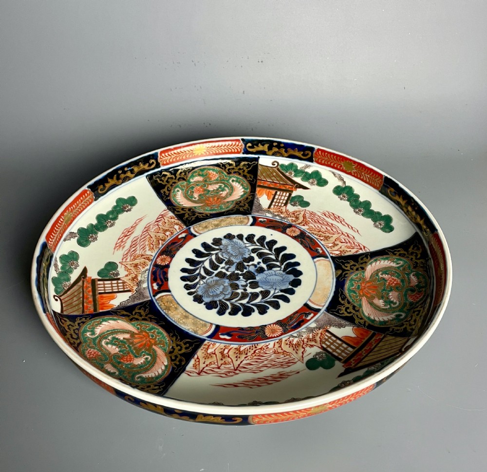 A large circular Japanese Imari porcelain shallow bowl featuring detailed panelled motifs in cobalt blue, iron-red, green, and gold hand-painted enamel. View VI