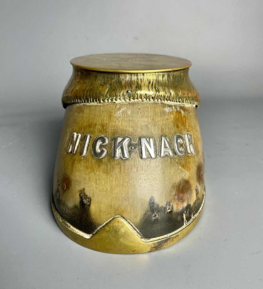 A Victorian horse hoof inkwell featuring brass mounts, a hinged brass lid, and silver lettering reading NICK-NACK.