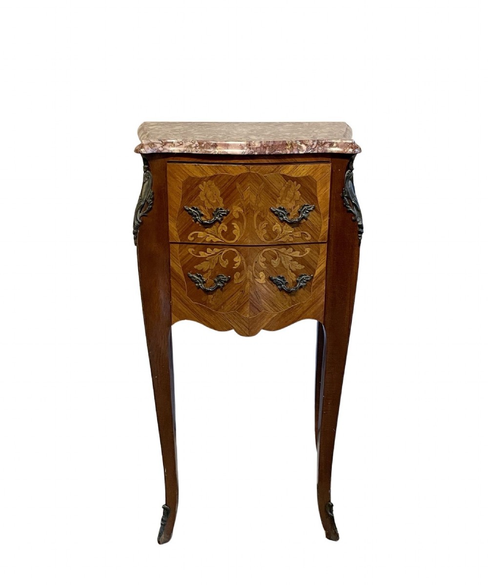A French Louis XV Revival bedside chest featuring floral marquetry inlays across two drawers, dark metal handles, slender cabriole legs, and a mottled reddish-brown marble top.