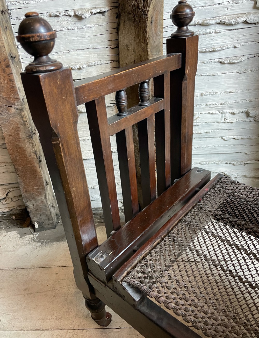 A dark wood Edwardian miniature bed with turned finials, castors, and a striped fabric mattress with matching pillow. View V