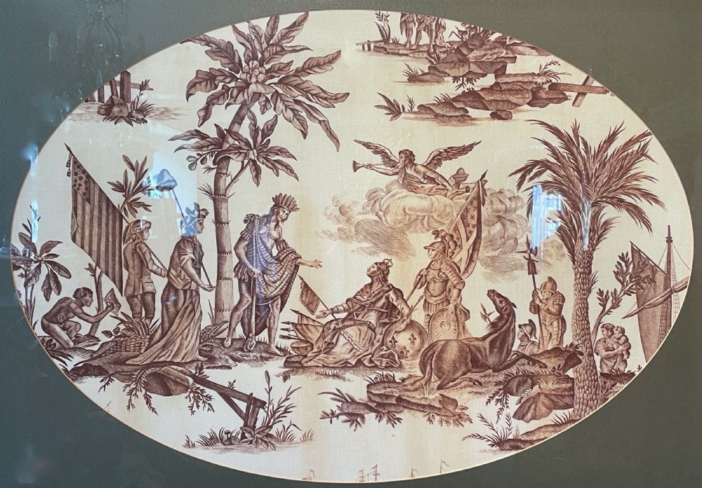 An oval copperplate-printed sepia textile fragment depicting an allegorical scene set inside a green mount and dark wooden frame. View II