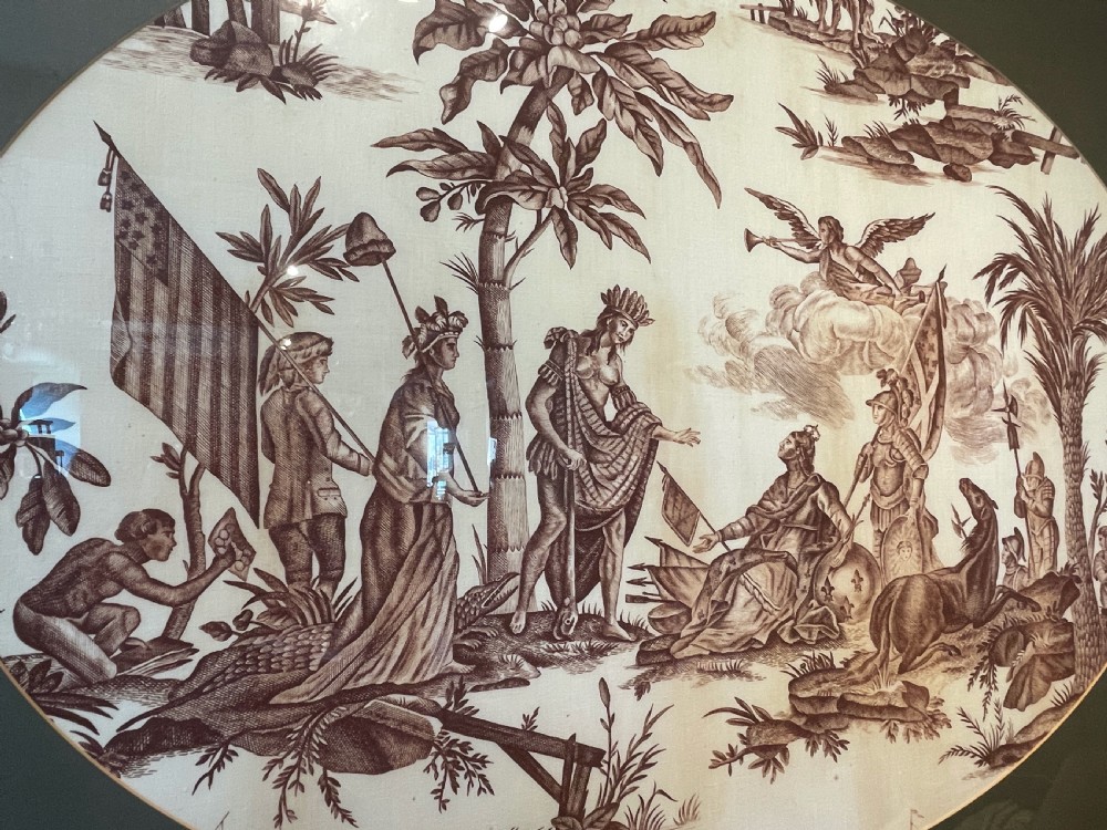 An oval copperplate-printed sepia textile fragment depicting an allegorical scene set inside a green mount and dark wooden frame. View III