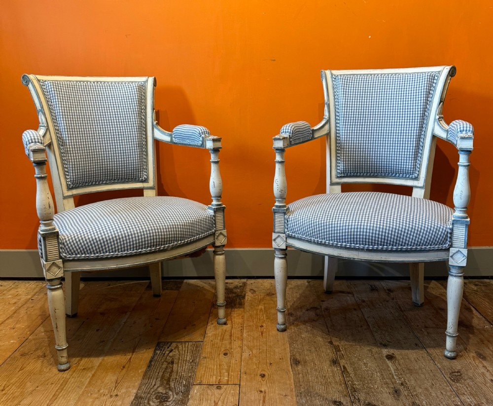 Pair of vintage French armchairs featuring off-white distressed painted frames, fluted turned front legs, and blue and white checked fabric upholstery. View II