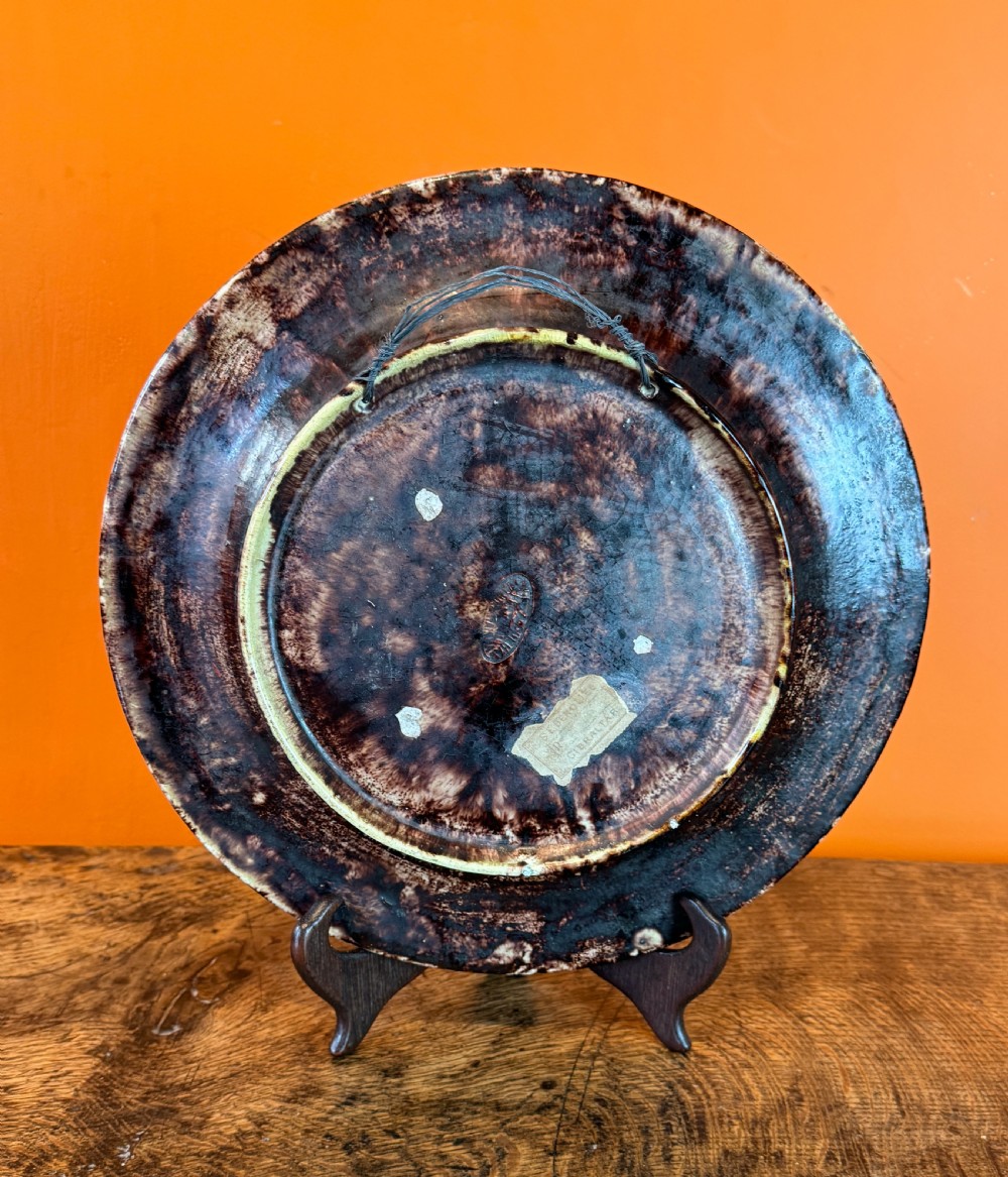 A circular 19th-century Portuguese majolica earthenware dish featuring high-relief ceramic fruit including grapes, strawberries, and oranges surrounded by green leaves. View III