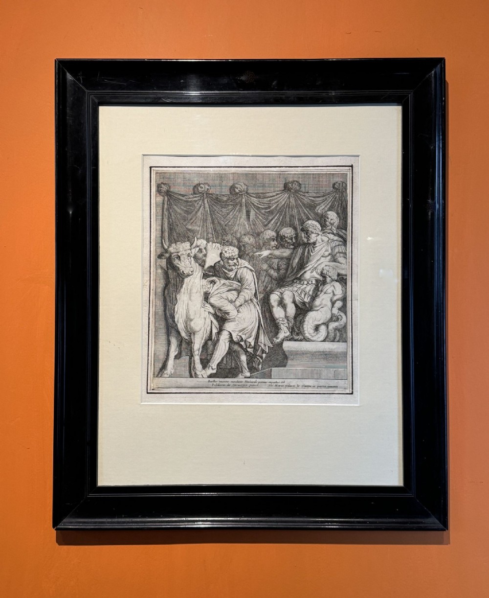 A framed black and white etching featuring classical figures and a bull within an ebonised wooden frame.