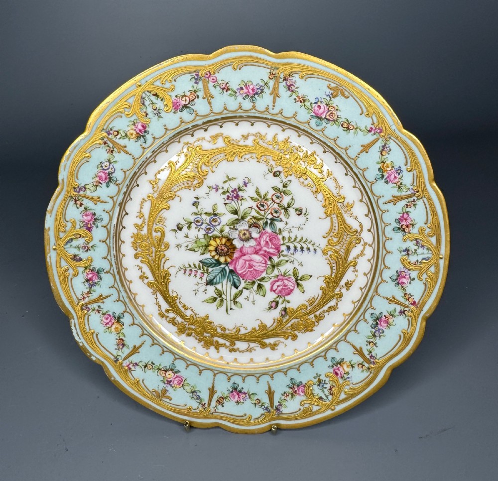 A circular 19th-century French porcelain cabinet plate featuring central hand-painted floral bouquets framed by elaborate gold scrollwork and a turquoise border.