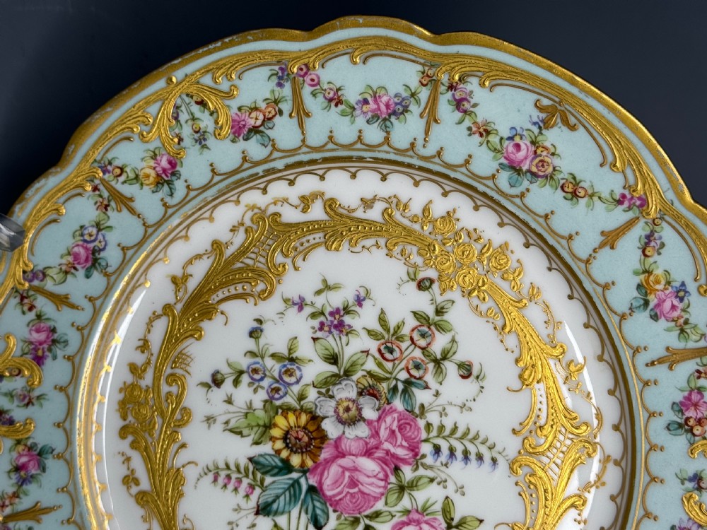 A circular 19th-century French porcelain cabinet plate featuring central hand-painted floral bouquets framed by elaborate gold scrollwork and a turquoise border. View V