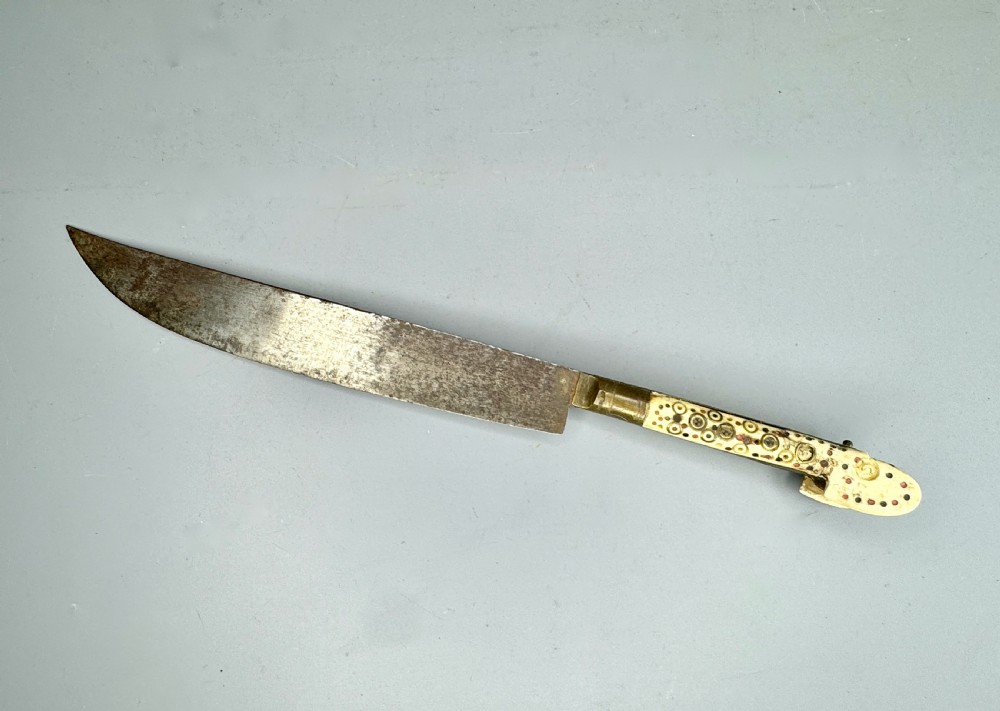 An antique nineteenth-century Balkan dagger featuring a curved steel blade and an off-white bone handle decorated with circular brass pin motifs.