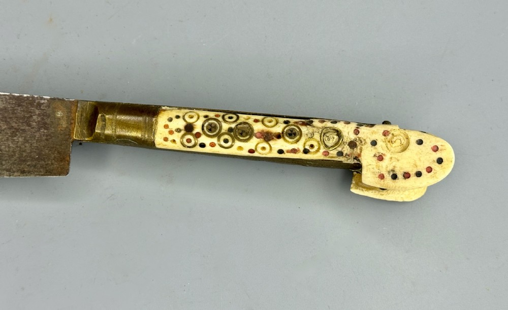 An antique nineteenth-century Balkan dagger featuring a curved steel blade and an off-white bone handle decorated with circular brass pin motifs. View II