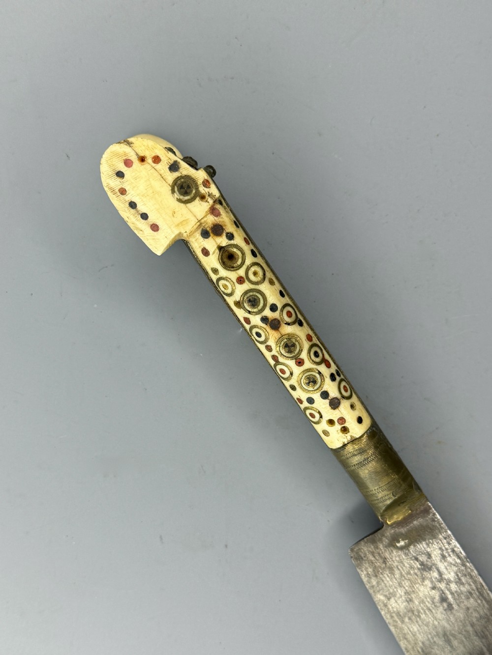 An antique nineteenth-century Balkan dagger featuring a curved steel blade and an off-white bone handle decorated with circular brass pin motifs. View IV
