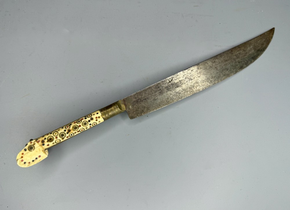 An antique nineteenth-century Balkan dagger featuring a curved steel blade and an off-white bone handle decorated with circular brass pin motifs. View V