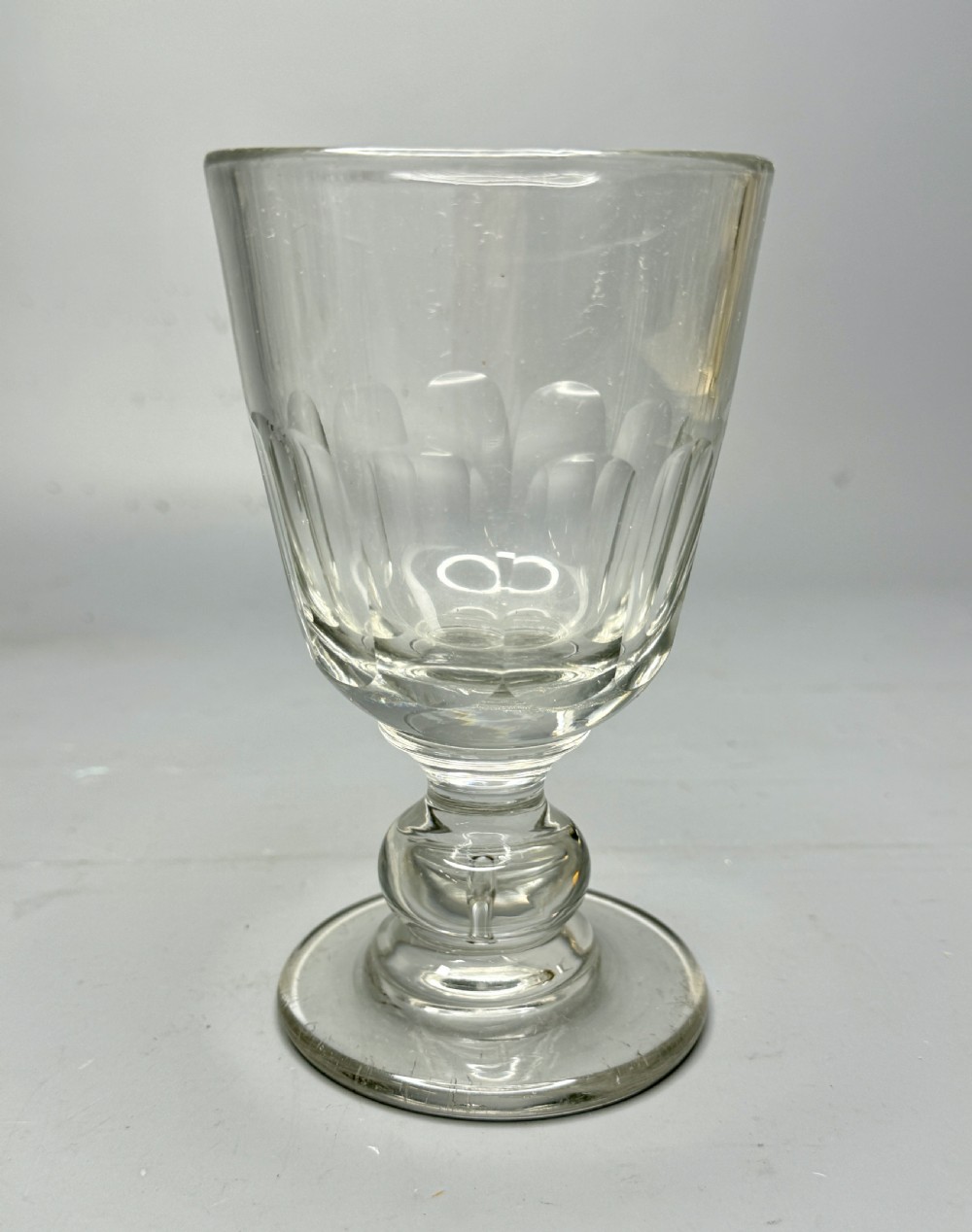 A clear Victorian glass rummer featuring a slice-cut bowl, a knopped stem, and a flat circular base.