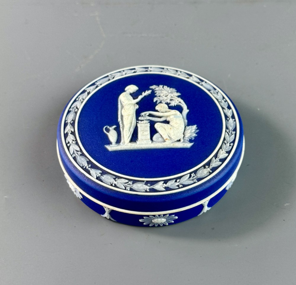 A circular royal blue jasperware patch box featuring white neoclassical relief figures on the lid and floral sprigging around the rim. View II