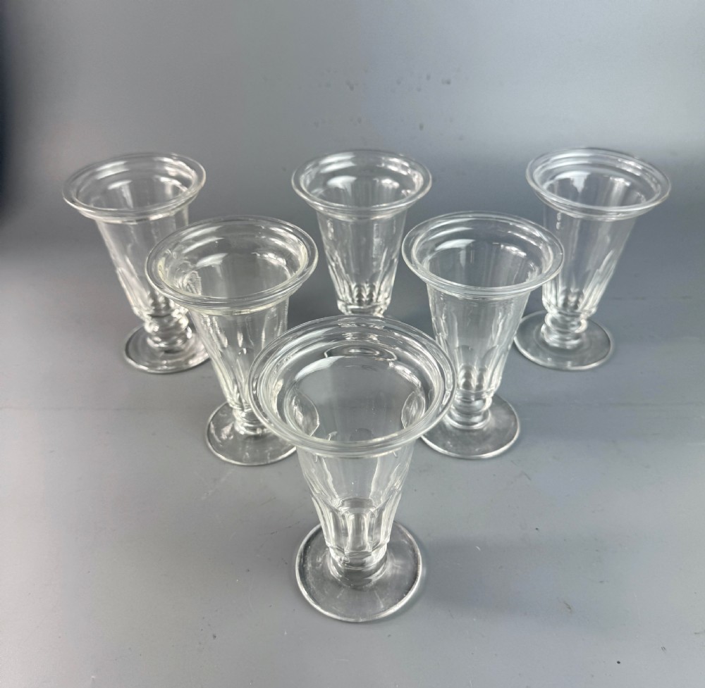 A set of six clear Georgian glass jelly cups featuring fluted tapered bowls, dish tops, knopped stems, and circular bases. View II